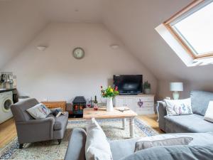 a living room with a couch and a tv at Jasmine Cottage in Little Witcombe