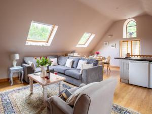 uma sala de estar com um sofá e uma mesa em Jasmine Cottage em Little Witcombe