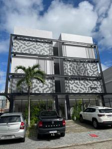 een gebouw met twee auto's ervoor geparkeerd bij Flat 313 Bauten Cabo Branco in João Pessoa