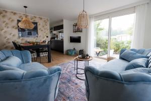 salon z niebieskimi kanapami i stołem w obiekcie Kek huisje aan de Maas w mieście Op-Andel