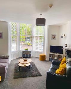 a living room with a couch and a table at Charles Alexander Short Stay - Clifton Drive Beach Retreat in Saint Annes on the Sea