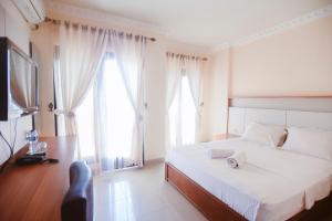 a bedroom with a bed and a tv and two windows at CHRYSANT HOTEL & RESORT in Oesapa-besar