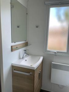 a bathroom with a sink and a mirror and a window at Mobil Home tout confort 6 personnes avec wifi in Onzain