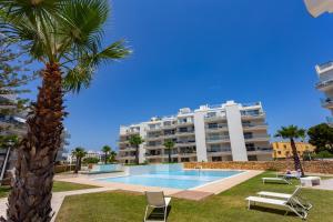 a palm tree and a building with a swimming pool at Denia Apartment Marina Real in Denia