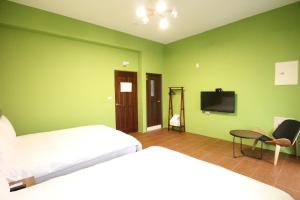 Schlafzimmer mit grünen Wänden, einem Bett und einem TV in der Unterkunft 蘑菇奇緣民宿 in Taitung