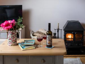 una mesa con una botella de vino y dos copas en Amber Cottage en Little Witcombe