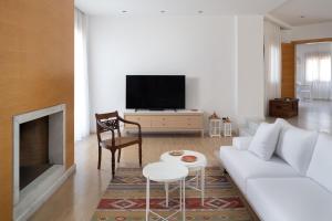 a living room with a white couch and a tv at Love White Villa in Ialysos