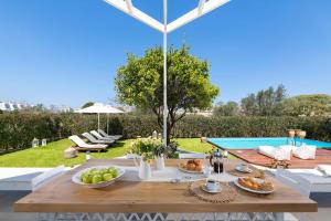 a table with food on it next to a pool at Love White Villa in Ialysos