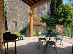 un patio con mesa, sillas y parrilla en maison de campagne en pierre, en Dégagnac