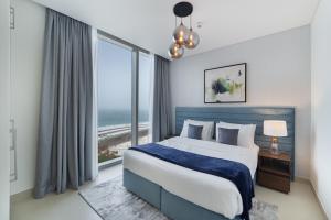 a bedroom with a large bed and a large window at Luxurious Apartments Dubai Marina Views - Pool & Gym by Sojo Stay in Dubai