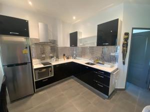 a kitchen with black cabinets and a stainless steel refrigerator at Relax and Rejuvenate in Rayong! in Rayong