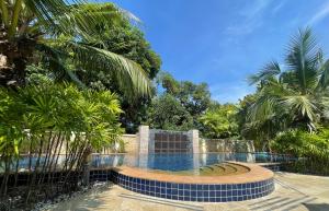 a swimming pool with palm trees and a fence at Relax and Rejuvenate in Rayong! in Rayong