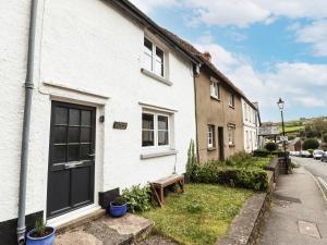 une maison blanche avec un banc à côté d'une rue dans l'établissement Lavender Cottage, à Okehampton