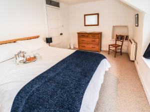 um quarto com uma grande cama branca e uma cómoda em madeira em Lavender Cottage em Okehampton