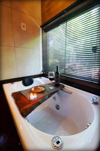 a bath tub with a bottle and a glass of wine at Cabana em meio a natureza com piscina. in Rodeio