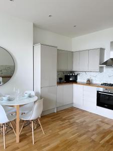 a kitchen with white cabinets and a table and chairs at Modern and light 2 bed flat in SW2 in London