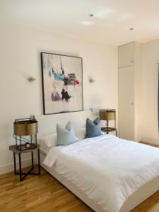 a bedroom with a large white bed with blue pillows at Modern and light 2 bed flat in SW2 in London