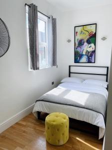 a bedroom with a bed and a yellow stool at Modern and light 2 bed flat in SW2 in London