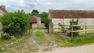uma antiga quinta com uma cerca e uma estrada de terra em La Maison de Ners em Pertheville-Ners