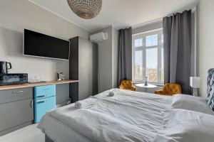 a bedroom with a bed and a desk and a tv at La Casa del Grand Apartments Sopot in Sopot