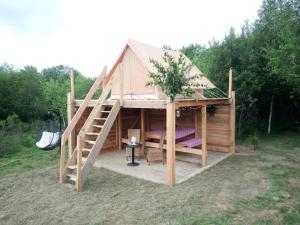 Una gran casa de madera con una escalera en un campo en Tente bivouac Élevage Girbal, en La Chapelotte