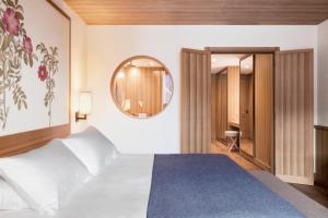 a bedroom with a white bed and a mirror at Faloria Mountain Spa Resort in Cortina dʼAmpezzo