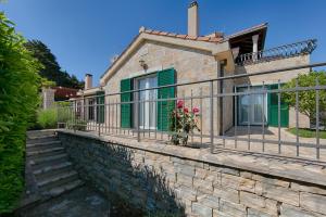 a house with green shutters and a stone wall at Villa Anja in Pražnice