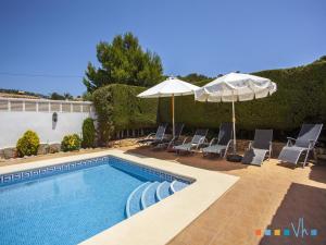 a swimming pool with two umbrellas and chairs and a pool at VH CostaBlanca - FONDA in Casas de Torrat