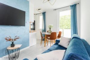 a living room with a blue couch and a table at Flatbook Apartamenty - Sztutowo Baltic Sun -A- z Basenem in Sztutowo
