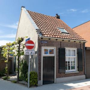 una pequeña casa de ladrillo con un cartel delante en Museumhuisje 013 en Tilburg