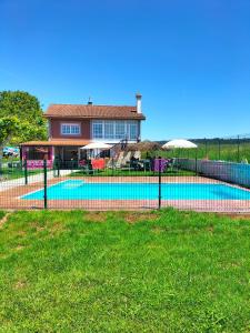 a fence in front of a house with a swimming pool at Pension Diana in O Pedrouzo