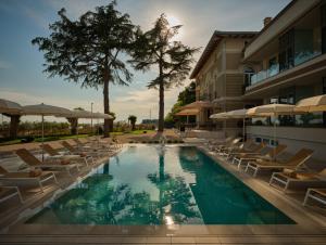 a swimming pool with lounge chairs and a building at Palazzo Rainis Hotel & Spa - Small Luxury Hotel - Adults Only in Novigrad Istria