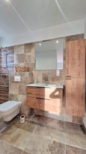 een badkamer met een wastafel, een toilet en een spiegel bij Petite maison en pierre in Afa