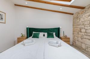 a bedroom with a large white bed with green accents at Apartment Augusto - Sea view in Pula