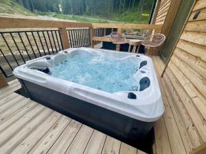 a hot tub on a deck with a table at Apartmany Demänovka Jasna in Belá