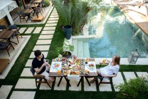 two people sitting at a table next to a pool at The ABC Hotel in Alaçatı