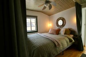 1 dormitorio con 1 cama con ventilador de techo y espejo en Casa Nórdica, en Chão de Lamas