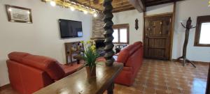 sala de estar con muebles de cuero rojo y TV en Casa Rural "La Cabaña de Andrés ", en Corrales