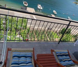 a balcony with two chairs and a view of the water at Apartmani Ivana in Tivat