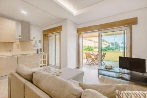 a living room with a couch and a tv and a kitchen at Furadouro Beach and Club Apartment in Ovar +23 photos
