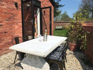 ein weißer Tisch mit einer Kerze auf einer Terrasse in der Unterkunft Delightful detached Cottage in Village Centre in Plymtree