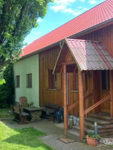 a wooden house with a roof and a patio at Jagdhaus auf dem Forsthof mit Sauna in Eckartsberga