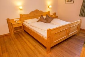 Cama grande de madera en habitación con suelo de madera en Residence Rosarela, en Badia