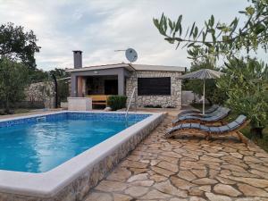 a swimming pool with two chairs and an umbrella at Villa Frane in Kneževići