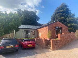 Zwei Autos parkten vor einem Backsteinhaus in der Unterkunft Delightful detached Cottage in Village Centre in Plymtree