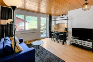 uma sala de estar com um sofá azul e um piano em Apartment next to Titlis Station em Engelberg