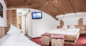 twee bedden in een kamer met een tv aan de muur bij Haus Tanja in Sölden