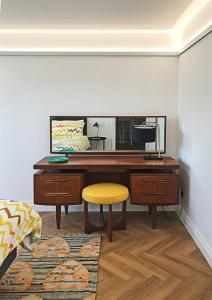 a desk with a yellow stool and a mirror at Ilfracombe Townhouse: restored historic home in Ilfracombe