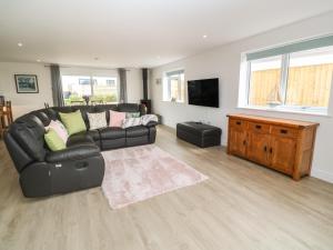 a living room with a black leather couch and a television at 3 Praa Cove in Penzance