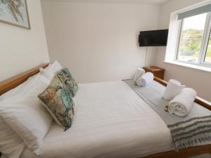 a bedroom with a bed with towels and a window at 3 Praa Cove in Penzance